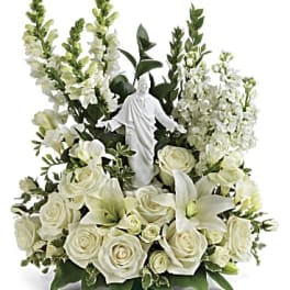 White floral arrangement with a small religious statue in the center
