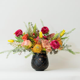 Colorful mixed flower arrangement in a dark decorative vase