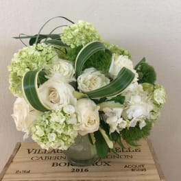 White roses and pale green hydrangeas arranged in a glass vase