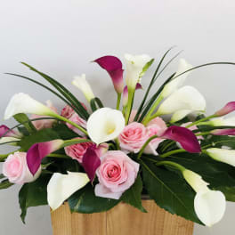 Pink roses and white-purple calla lilies in a wooden container