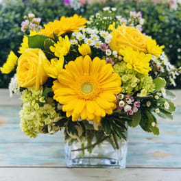 Yellow roses and daisies arranged in a clear glass vase