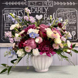 Mixed pink, white, and blue flowers arranged in a white vase