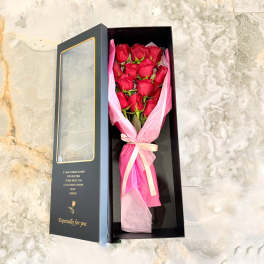 Boxed bouquet of red roses wrapped in pink tissue