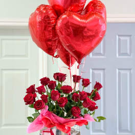 Red roses in a silver gift bag with red heart balloons