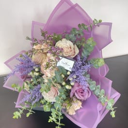 Bouquet of pink and lavender roses wrapped in purple paper