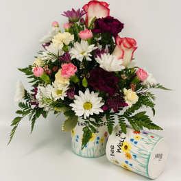 Mixed bouquet of daisies, carnations, and roses in a decorated container