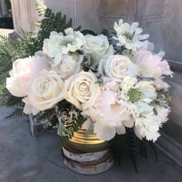 Ivory and white rose and peony arrangement with ferns in a gold container on a wood base