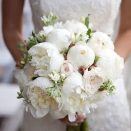 Bride holding a white wedding bouquet with round blooms