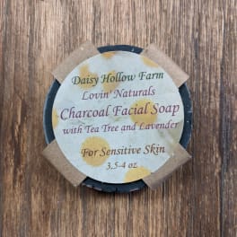 Round charcoal facial soap bar with a labeled paper top