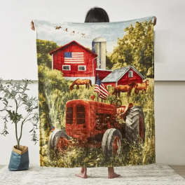 Person holding a blanket printed with a red barn and tractor scene