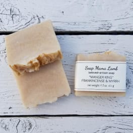 Two bars of beige artisan soap on a white wooden surface