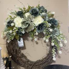 Floral wreath with blue-green and white blooms on a twig base