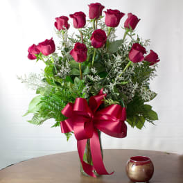 Bouquet of red roses in a glass vase with a large red ribbon