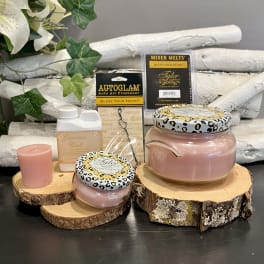 Pink candles and fragrance products on wood slices with faux ivy