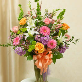 Mixed bouquet of pink, orange, white, and purple flowers in a glass vase