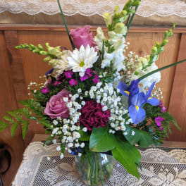 Mixed bouquet in a glass vase with roses, daisies, iris, and snapdragons