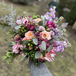 Handheld bouquet of pink, peach, and lavender flowers