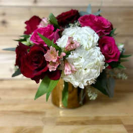 Bouquet of red and pink roses with white hydrangeas in a gold vase