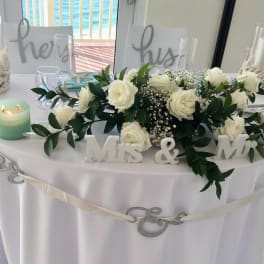White rose centerpiece on a decorated wedding table with candles