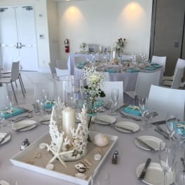 White floral centerpieces on round banquet tables with seashell decor