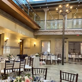 Floral centerpieces on round banquet tables in a decorated reception hall