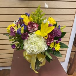 Colorful mixed bouquet in a glass vase with a yellow ribbon