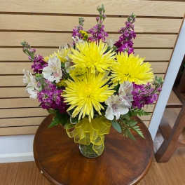 Bouquet of yellow chrysanthemums and purple flowers in a glass vase