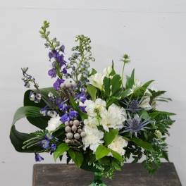 White and purple floral arrangement in a green glass vase