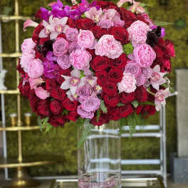Large bouquet of red, pink, and purple flowers in a clear glass vase