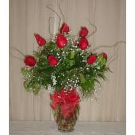 Red roses arranged in a clear glass vase with baby's breath