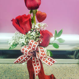 Red roses arranged with baby's breath and a heart decoration in a glittery high-heel vase