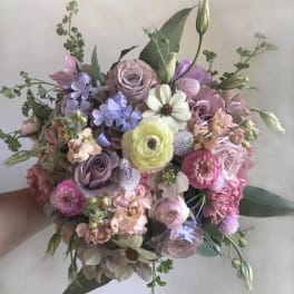 Handheld bouquet of pastel flowers in pink, lavender, and cream