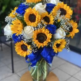 Bouquet of sunflowers and blue and white roses in a glass vase