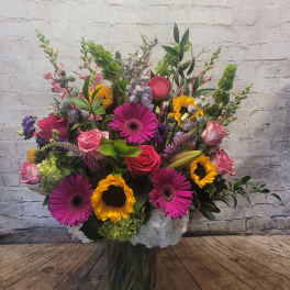 Mixed bouquet in a clear glass vase with pink, yellow, and purple blooms