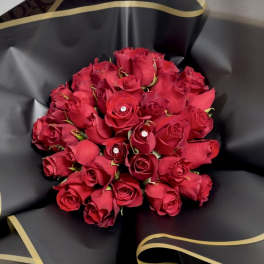 Bouquet of red roses wrapped in black paper with gold trim