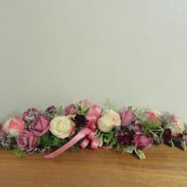 Low floral arrangement with pink and cream roses and a pink ribbon