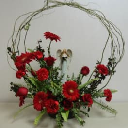 Red floral arrangement with an angel figurine in a circular twig frame