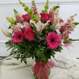 Pink and white mixed bouquet in a glass vase with a pink ribbon