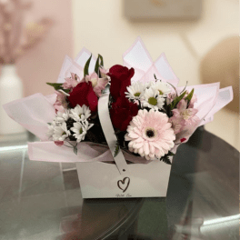 Bouquet of red roses, pink gerbera daisies, and white daisies in a gift box