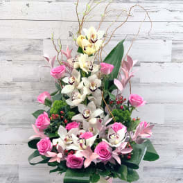 Pink roses and white orchids in a tall pink box arrangement