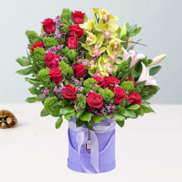 Bouquet of red roses and yellow orchids in a lavender box