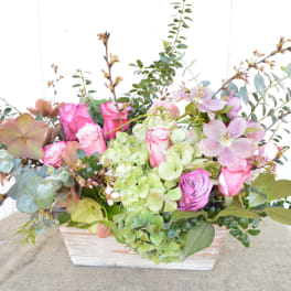 Pink roses and green hydrangeas in a white wooden box with eucalyptus
