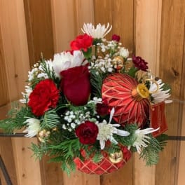 Red and white floral arrangement with ornaments in a decorative container