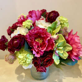 Pink and red floral arrangement in a textured silver vase