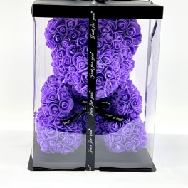 Purple rose teddy bear in a clear gift box with black ribbon
