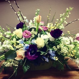 Low floral centerpiece with mixed roses and tulips in a container