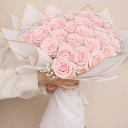 Bouquet of pale pink roses wrapped in white paper with gold trim