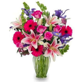 Mixed bouquet of pink lilies, roses, and gerbera daisies in a glass vase