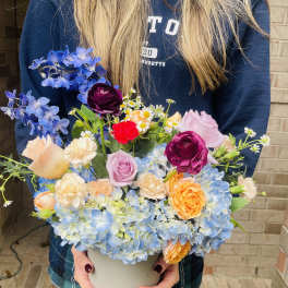 Mixed bouquet in a white vase with blue hydrangeas and roses