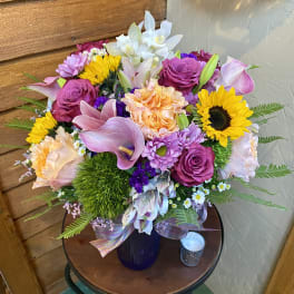 Mixed bouquet with sunflowers, roses, lilies, and calla lilies in a vase